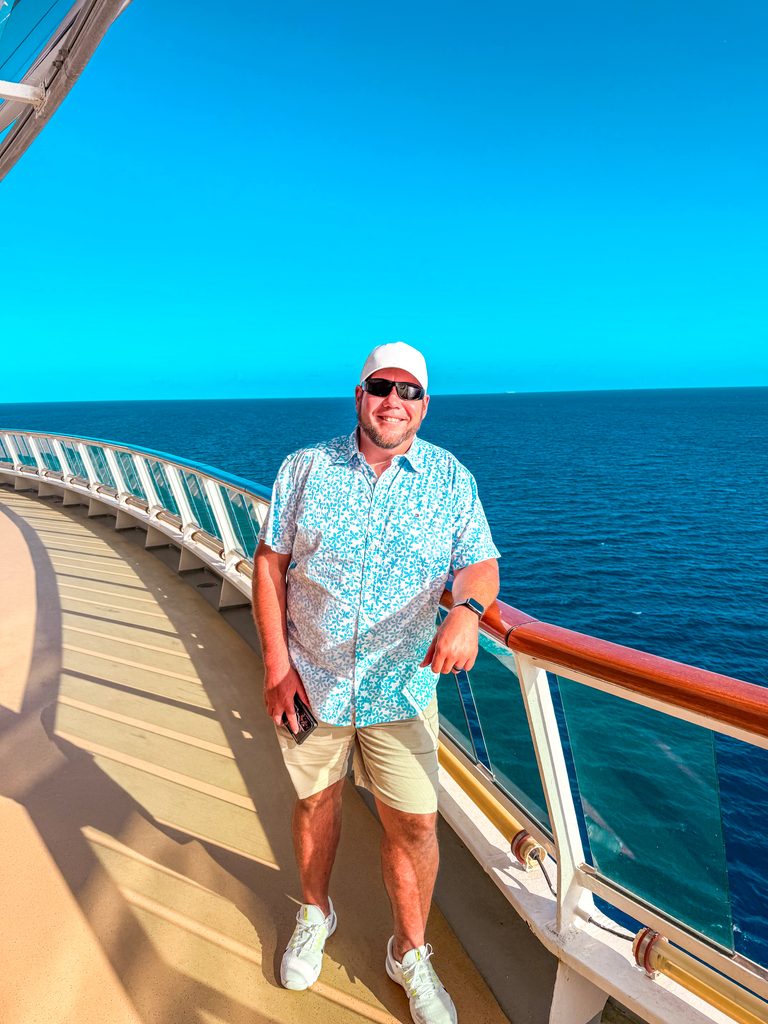 Jesse smiling on a cruise ship deck with the blue ocean behind him